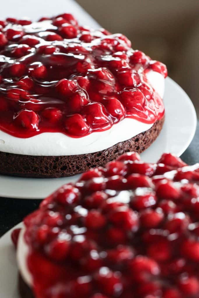 2 Black Forest Cakes on plates topped with cherry pie filling.