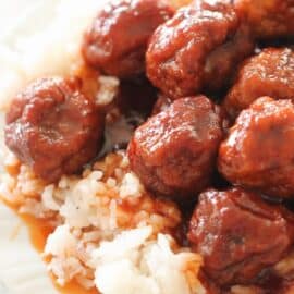 meatballs in sweet sauce over rice on a white plate