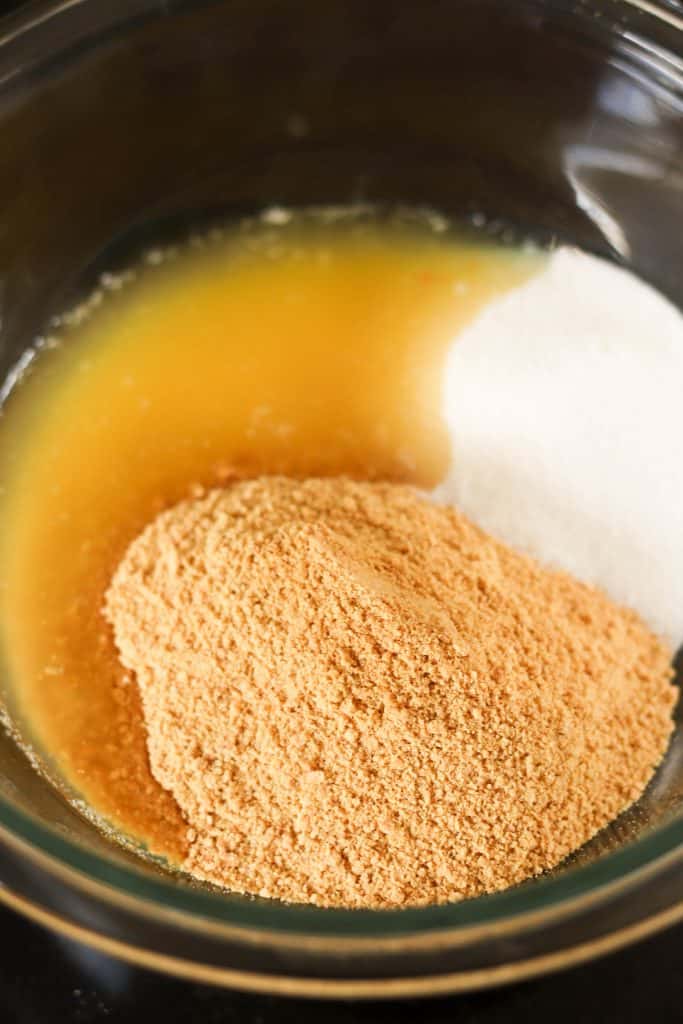 Graham cracker crumbs in a mixing bowl with melted butter.