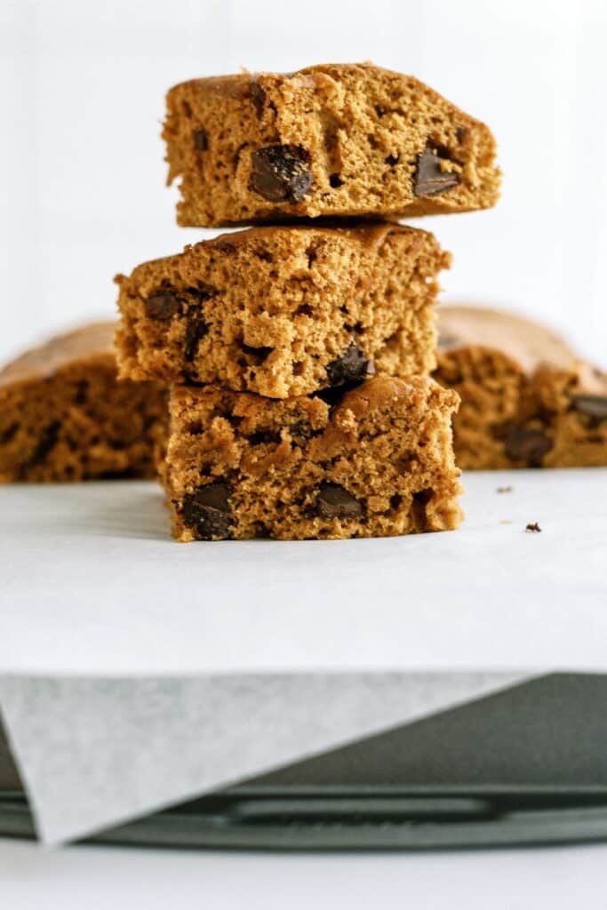 A stack of four rectangular slices of chocolate chip cake sits on a piece of parchment paper.