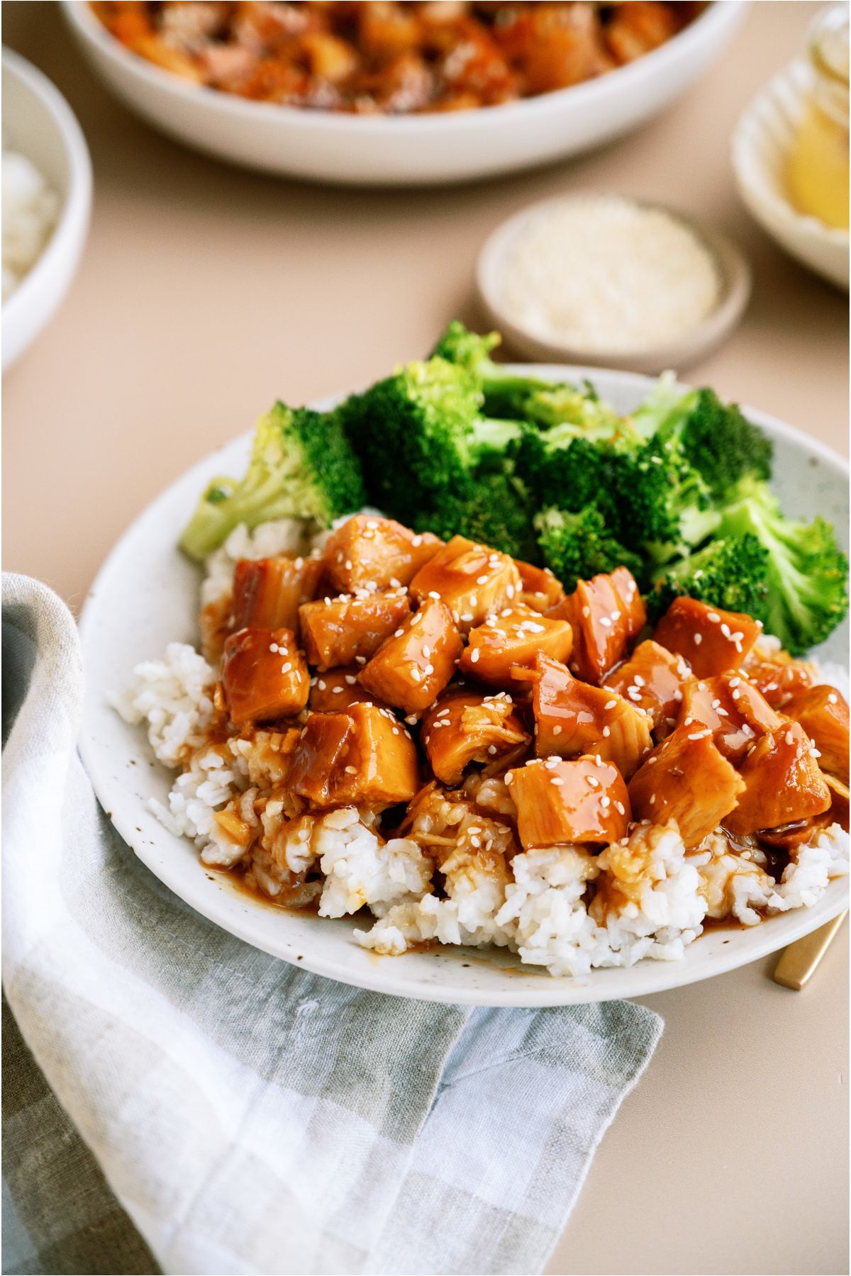 A plate of Slow Cooker Honey Sesame Chicken over rice with broccoli on the side.