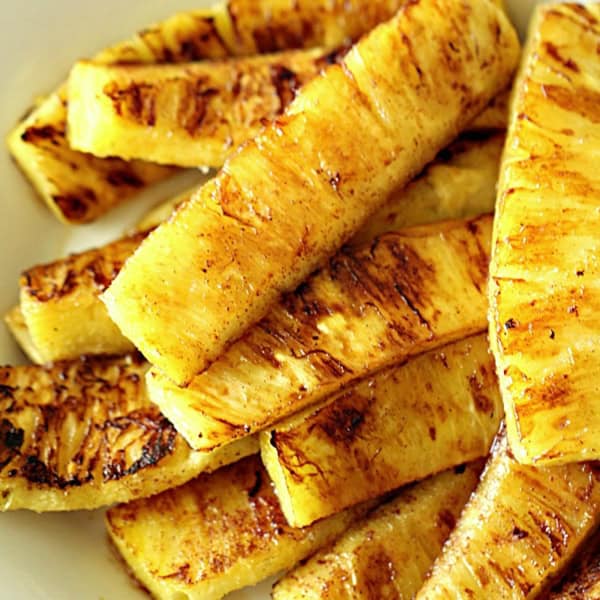 Grilled pineapple slices arranged on a white plate.