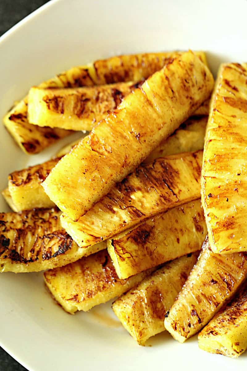 Grilled pineapple slices arranged on a white plate.