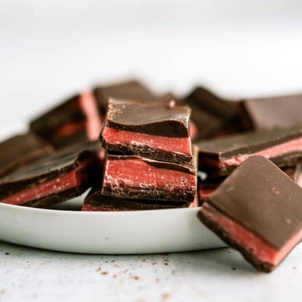 Valentine's Day chocolate thin mints cut into squares with some laying on a serving dish and others around the dish.