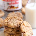 A stack of Peanut Butter Nutella Swirl Cookies with a jar of nutella in the background and a glass of milk off to the side.