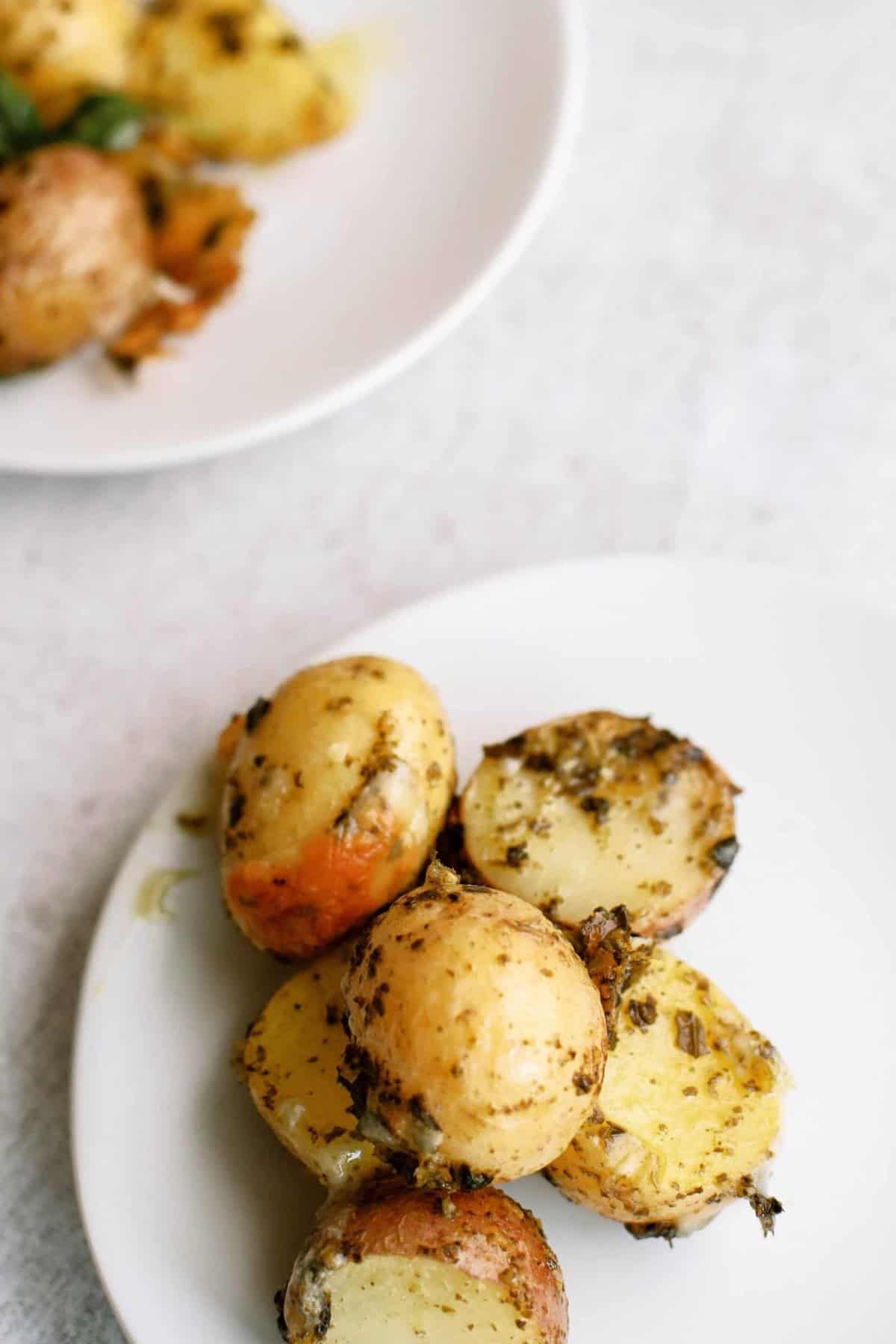 Slices of roasted potatoes seasoned with herbs on a white plate.