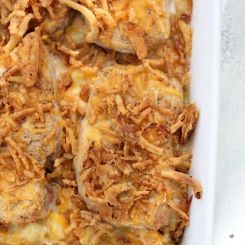 A close-up of a baked casserole dish filled with golden brown, crispy fried onions on top of melted cheese.