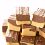 A stack of chocolate and peanut butter fudge cubes arranged in a pyramid shape. The fudge has a creamy texture with distinct chocolate and peanut butter layers.