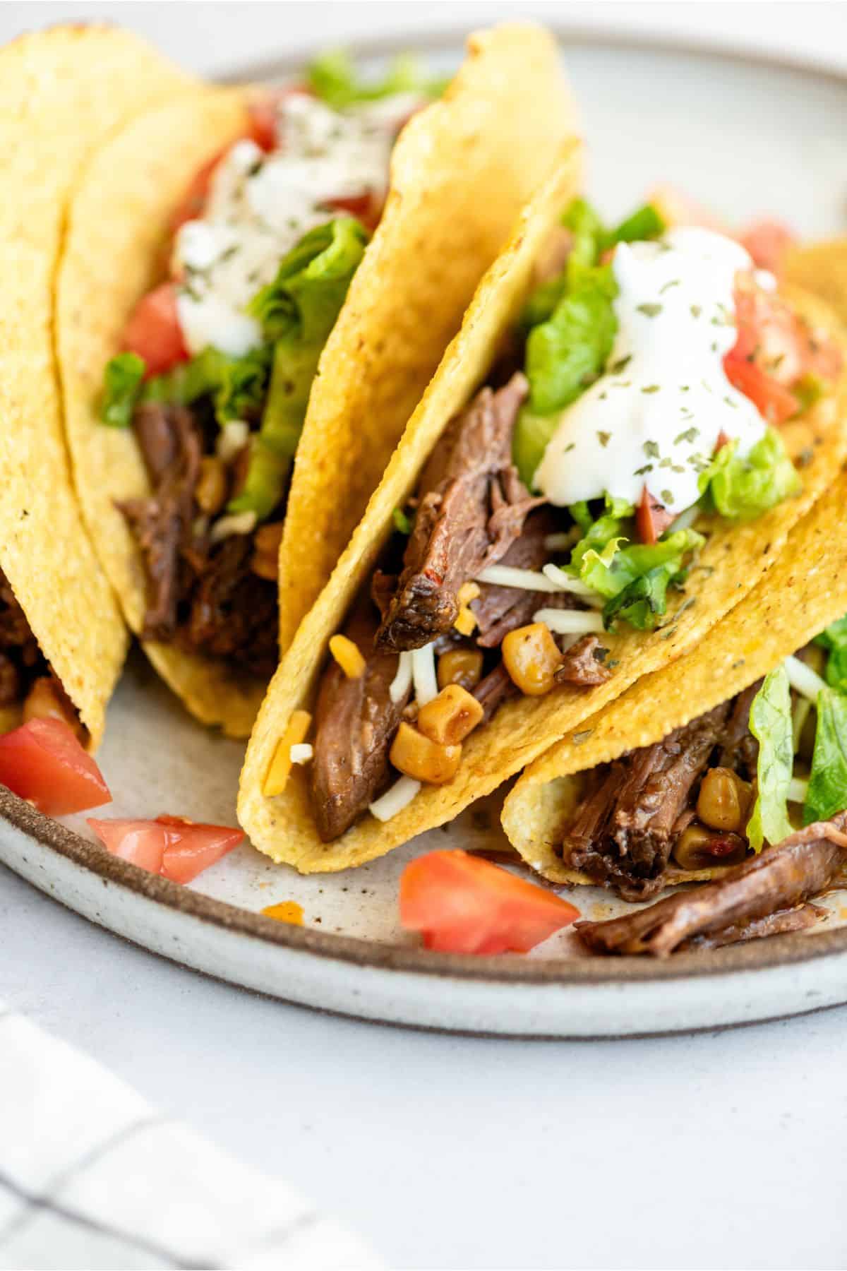 Slow Cooker Shredded Beef Tacos on a plate with toppings