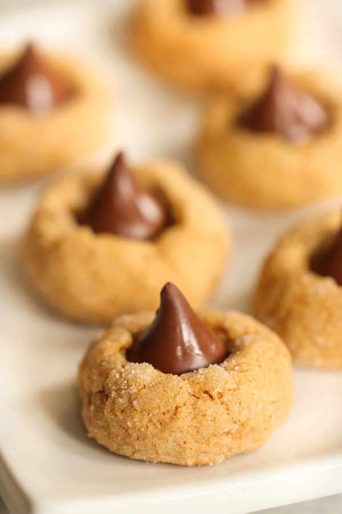 Close-up of pumpkin blossom cookies topped with chocolate kisses on a white plate.