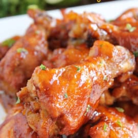 A close-up of honey chipotle chicken wings garnished with herbs, served on a white plate.