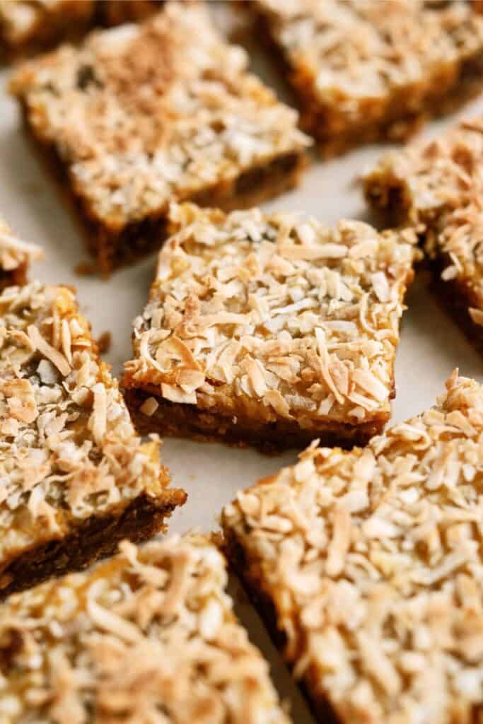 A close-up of several coconut-topped dessert bars arranged on a light surface.