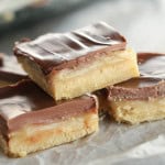 Homemade Twix Bars cut into squares and stacked on top of a serving tray.