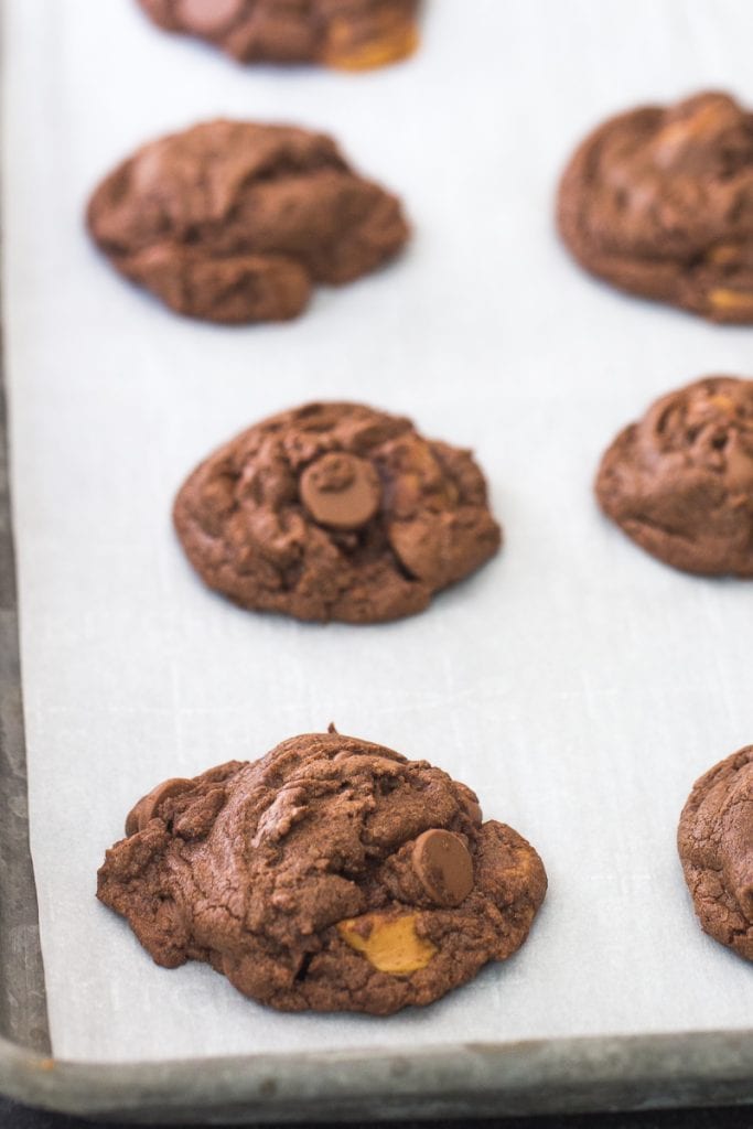 Fresh baked Chocolate Caramel Nutella Cookies on a lined baking sheet.