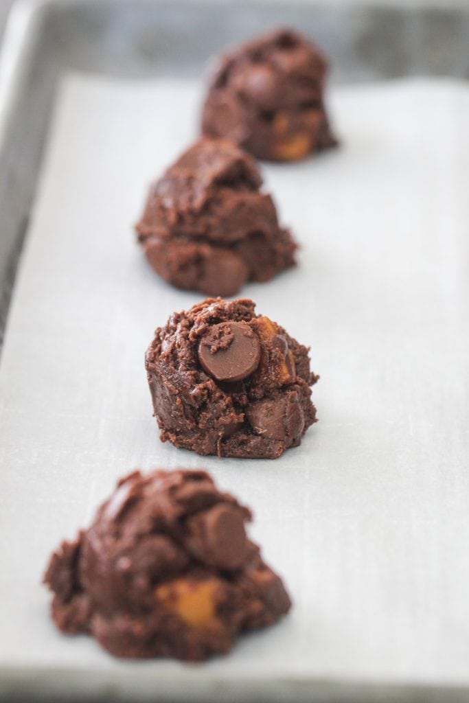 Chocolate Caramel Nutella Cookie dough balls on a lined baking sheet.