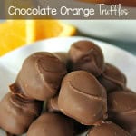 Chocolate Orange Truffles on a white serving plate with fresh oranges and orange slices in the background.