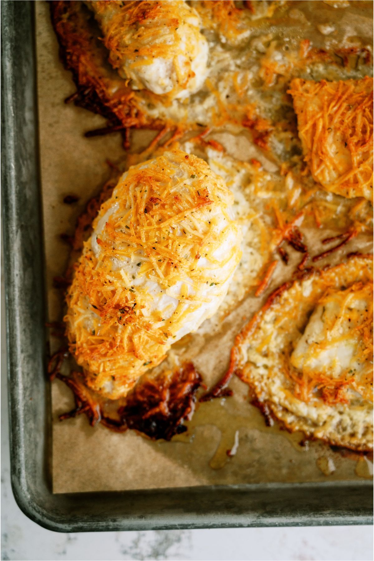 Baked Cheesy Ranch Chicken Breasts on a baking sheet lined with parchment paper.