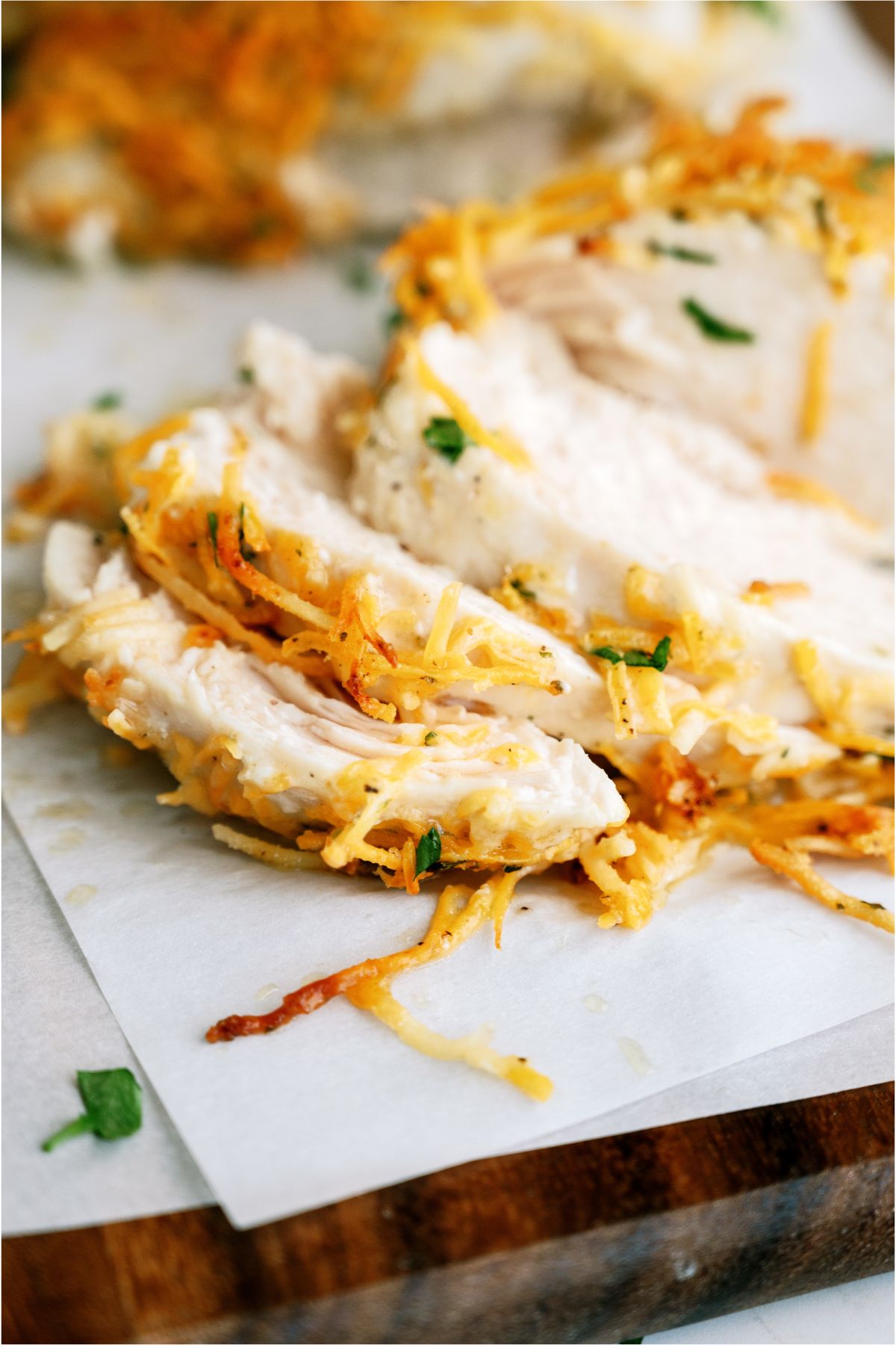 One cheesy ranch chicken sliced on a cutting board with one cheesy ranch chicken breast in the background.