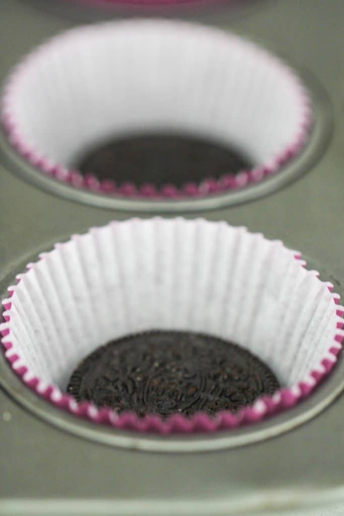 An oreo cookie in a cupcake liner in a cupcake tin.