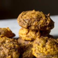 Close-up of a pile of homemade cookies with a golden-brown color, resting on a gray surface.