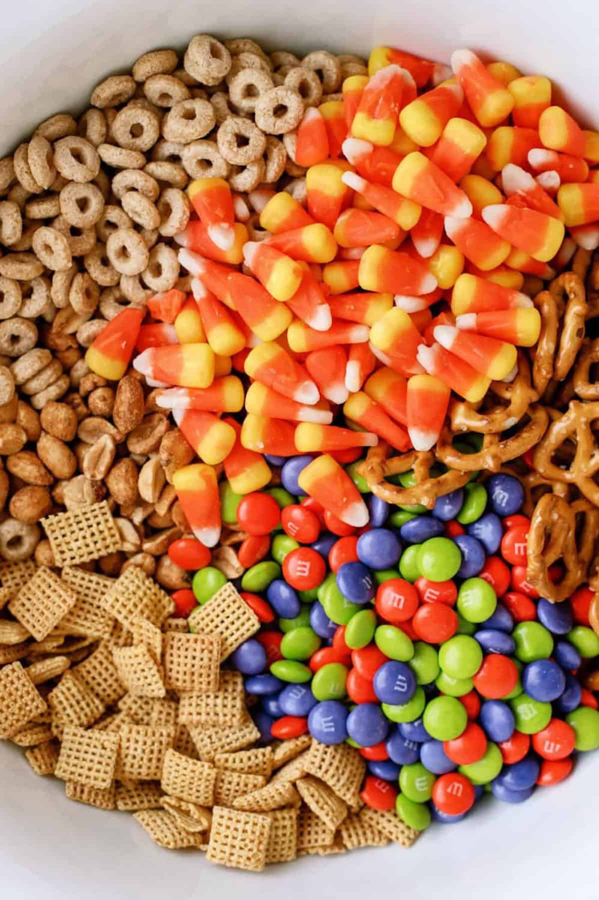 cheerios, chex, peanuts, candy corn, and M&Ms in a bowl