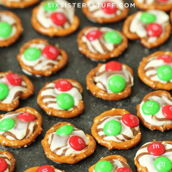 A tray of pretzel treats topped with melted chocolate and red and green candies.