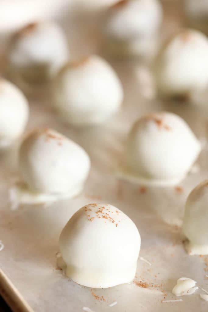 White Chocolate covered No Bake Gingerbread Cookie Truffles topped with sprinkles of nutmeg on a baking sheet.