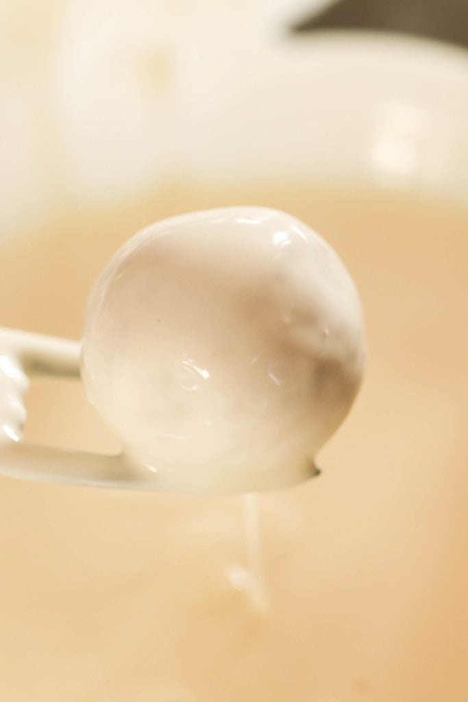 Lifting a No Bake Gingerbread Cookie Truffle out of melted white chocolate.