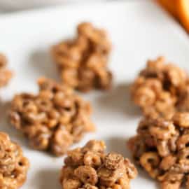 Close-up of a white plate holding several clusters of cereal and melted marshmallows, peanut butter breakfast bites