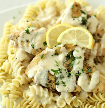 chicken over pasta topped with creamy lemon sauce and lemon slices