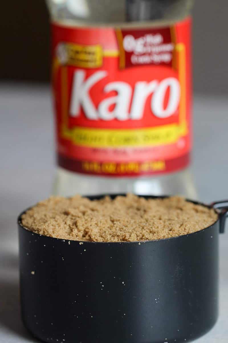 A bottle of Karo corn syrup with a cup of packed brown sugar in a measuring cup in front.