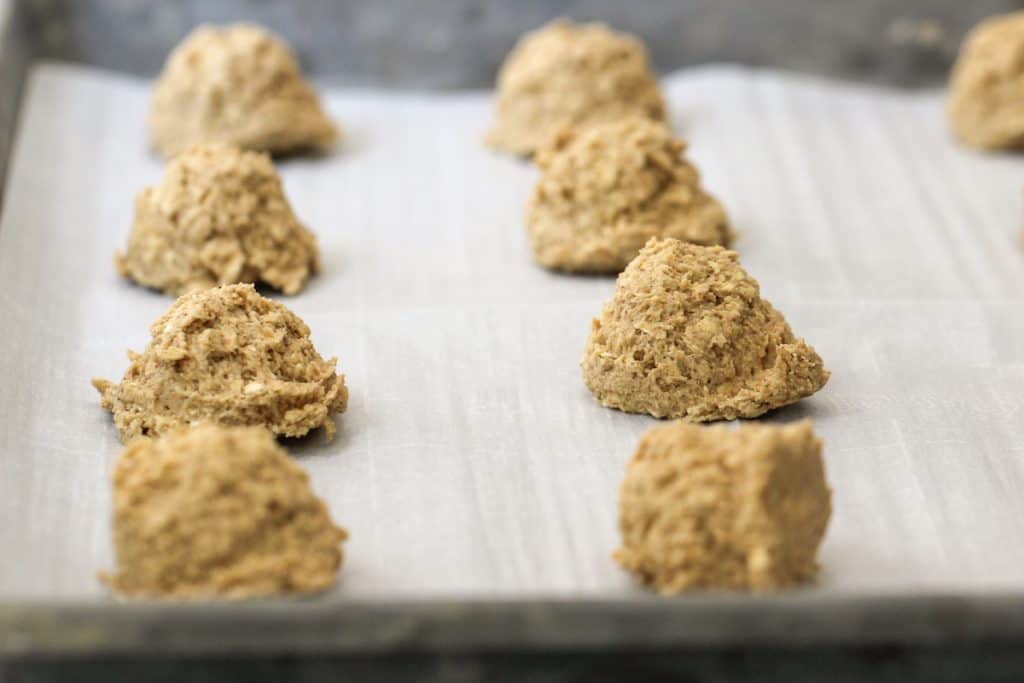 Oatmeal cookie dough balls on a baking sheet lined with parchment paper.