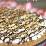 A S'mores Dessert Pizza on a red and white checkered table cloth.