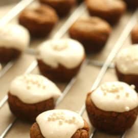 Small round cookies topped with white icing and sprinkles, arranged on a wire rack.