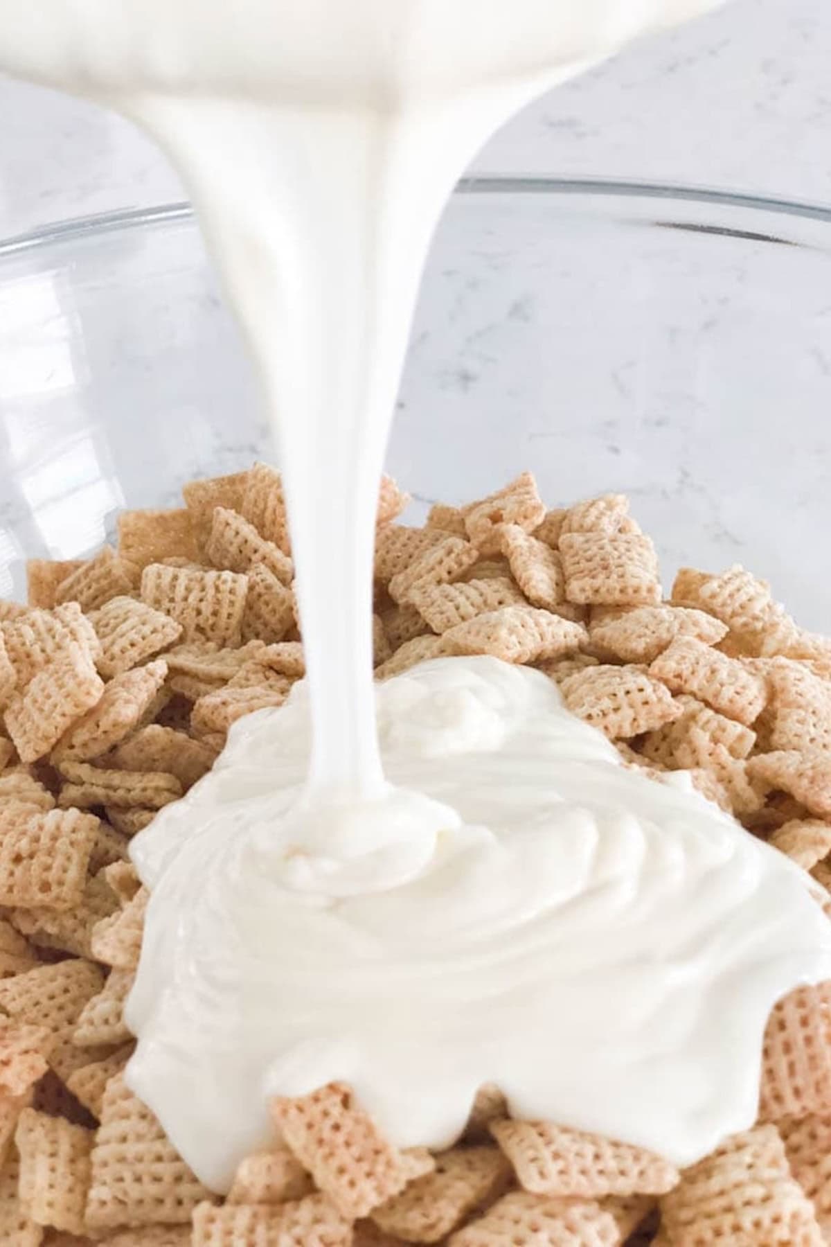 A bowl of cereal squares being topped with a generous pour of batter