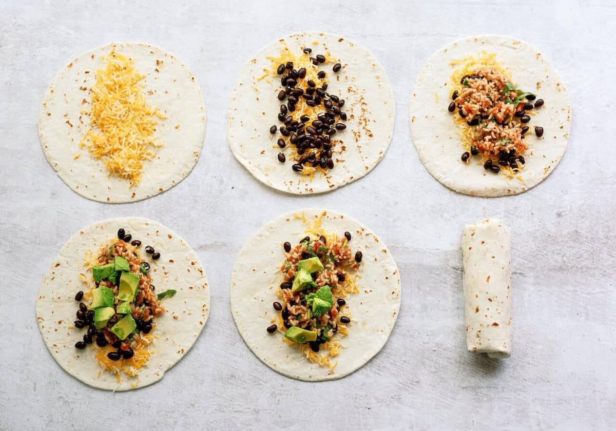 Five tortillas with varying fillings of cheese, black beans, rice, and avocado, arranged on a surface; one is rolled into a burrito.