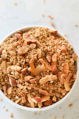 A large white bowl sitting on a counter filled to the top with Almond Butter Granola.