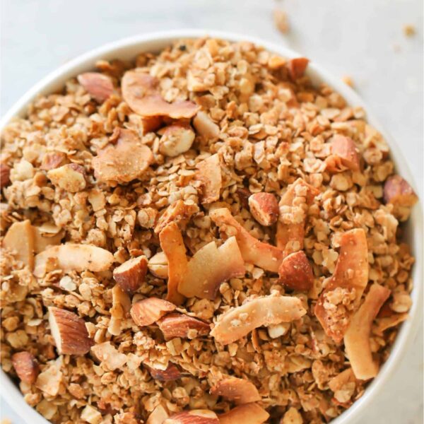 A large white bowl sitting on a counter filled to the top with Almond Butter Granola.