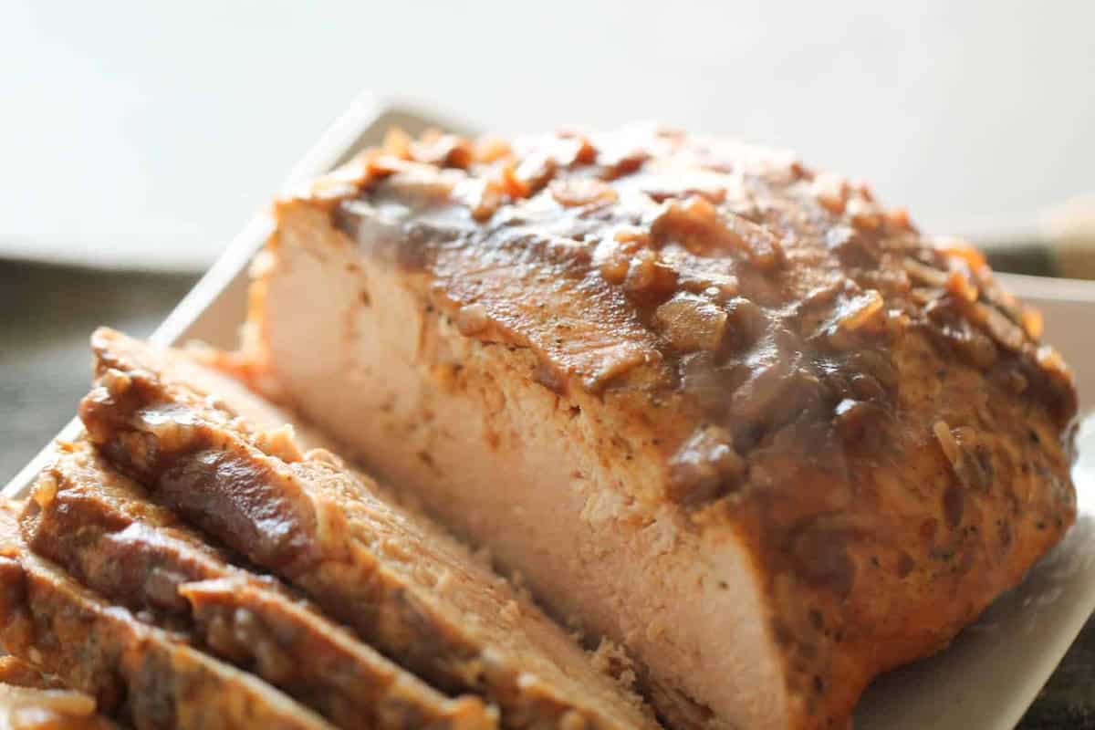 Sliced cranberry turkey breast on a rectangular white plate. The meat is browned and appears moist, with visible seasoning and a slight steam indicating it is freshly cooked.