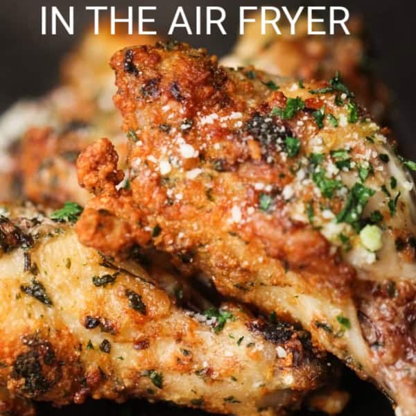 Close-up of garlic parmesan chicken wings cooked in an air fryer, garnished with herbs and grated parmesan.