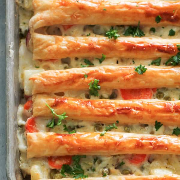 Rectangular dish filled with a baked, layered pastry topped with cheese, herbs, and carrots.