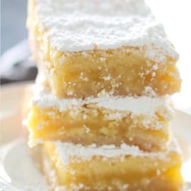 Lemon Bars stacked on plate with powdered sugar