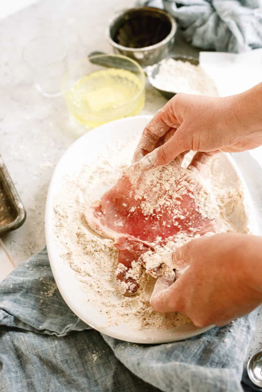 Dredging pork chop in flour for frying