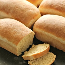 loaves of bread on cutting board with twoslices