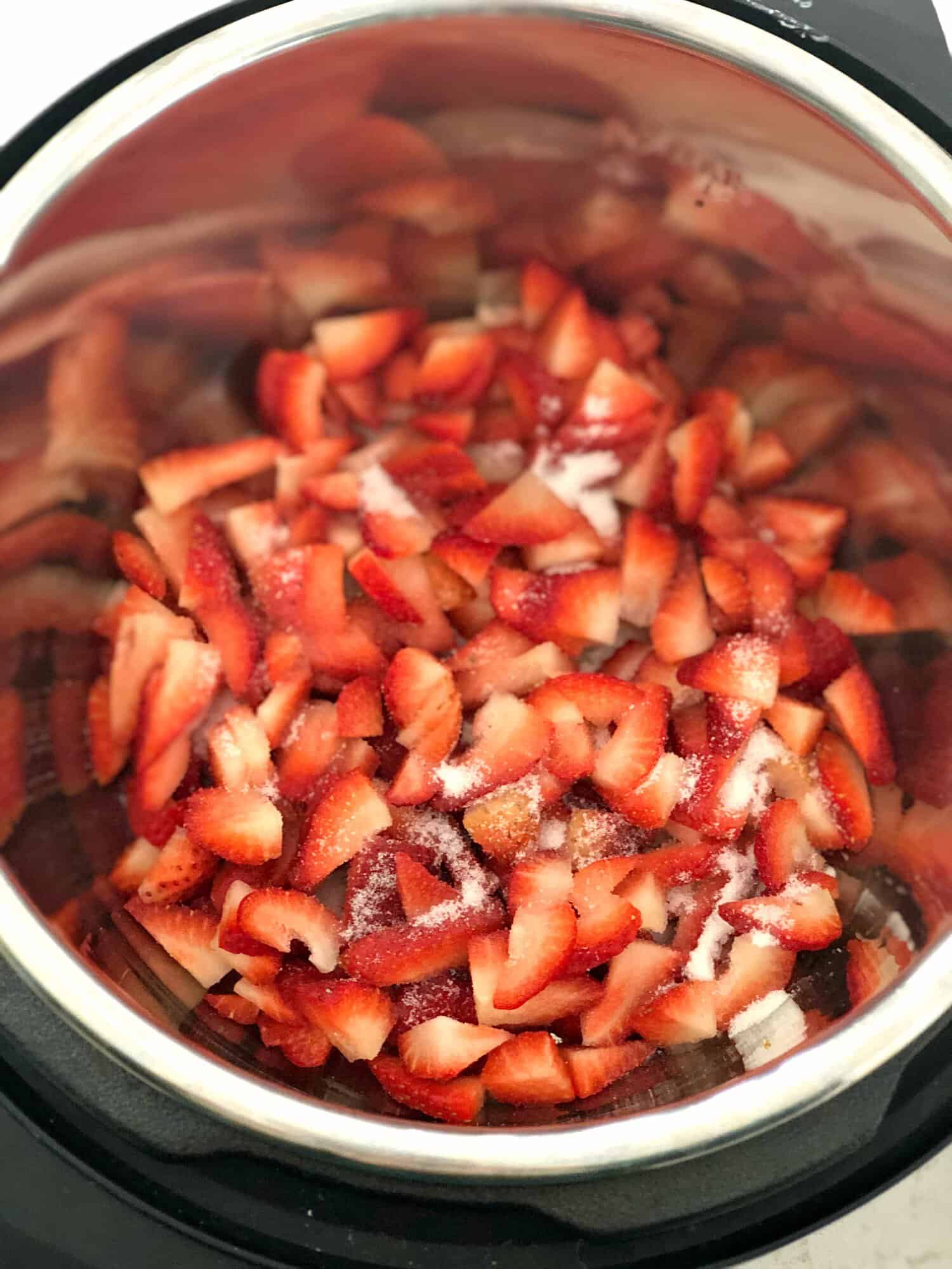 Diced strawberries in the instant pot with sugar sprinkled on top