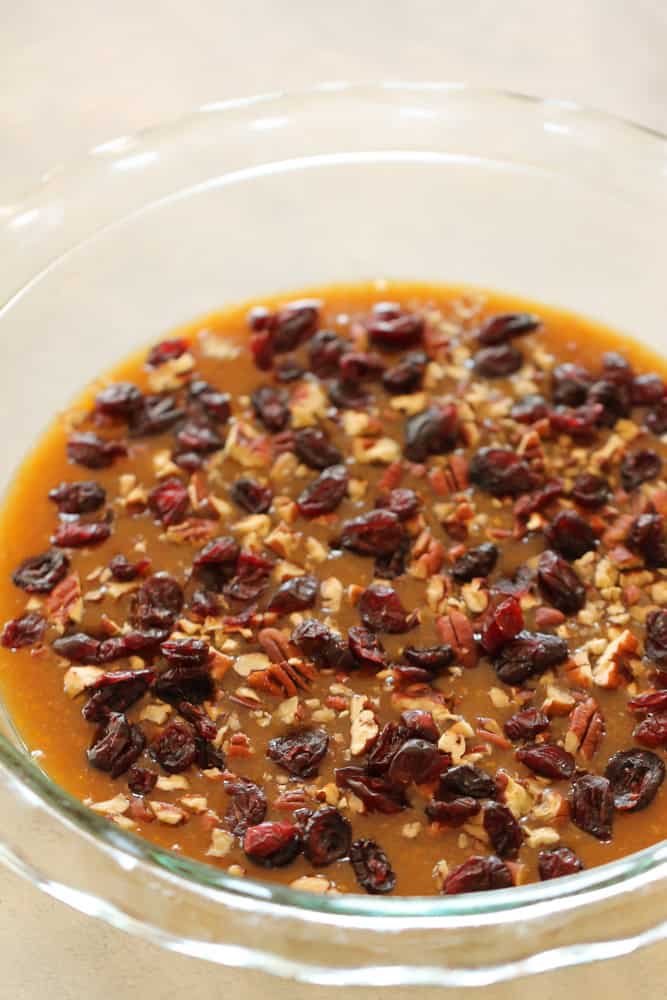 Brown sugar mixture topped with craisins on the bottom of a pie plate