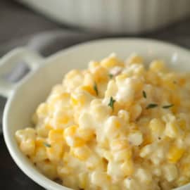 A bowl filled with creamy corn casserole, garnished with a small amount of chopped herbs.