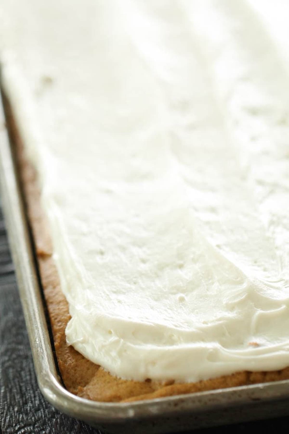 A close-up image of a frosted sheet cake in a metal baking pan.