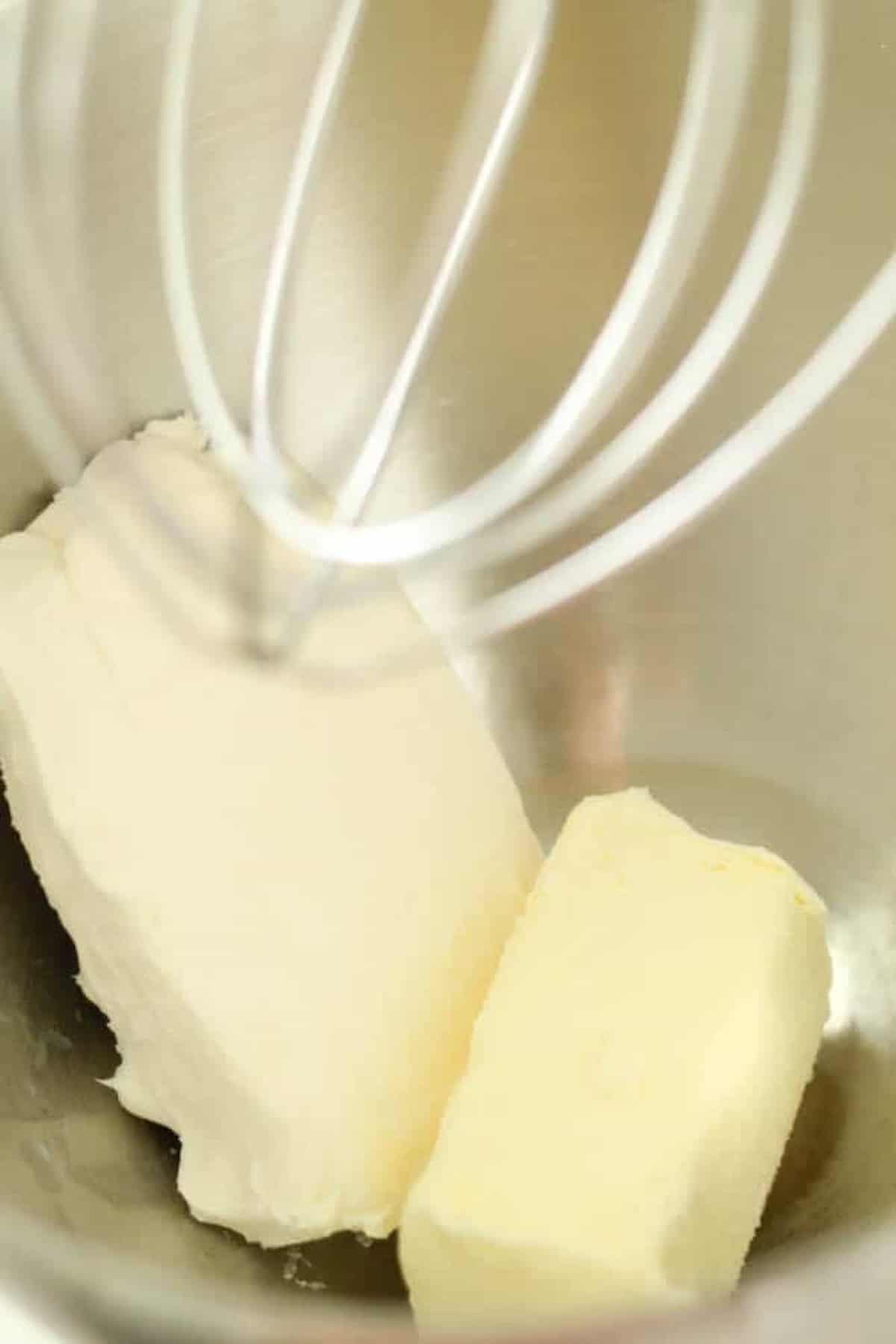 Metal whisk and blocks of butter in a mixing bowl.