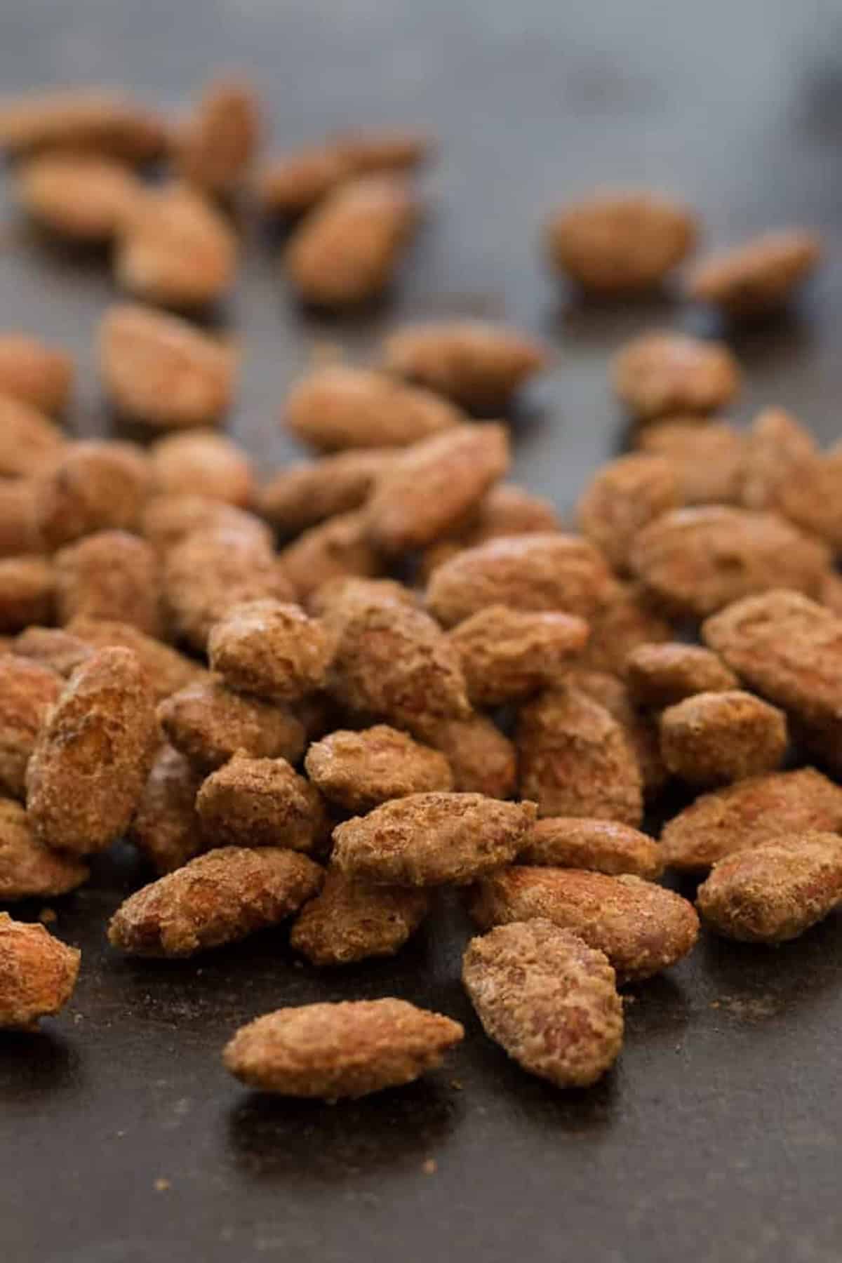 A close-up of numerous sugar-coated almonds scattered on a dark surface.